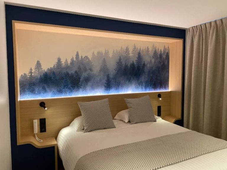 Tête de lit avec éclairage intégré et décor de forêt dans une chambre du Brit Hôtel, conçue par JoyDesign Intérieur.