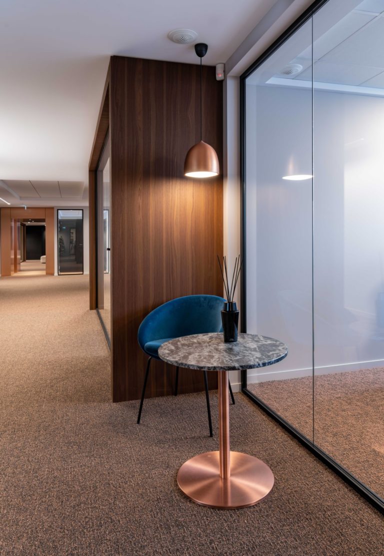 Coin de détente avec une table en marbre et une chaise bleue dans un cabinet d'avocat, design en cuivre et noir, par JoyDesign Intérieur.