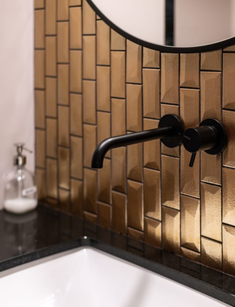 Détail d'un lavabo avec un robinet noir et une mosaïque cuivrée, conçu par JoyDesign Intérieur pour un cabinet d'avocat.