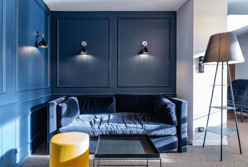 Coin détente chic avec un canapé bleu marine, des murs bleu foncé et des accents de cuivre et noir, conçu par JoyDesign Intérieur pour un cabinet d'avocat.