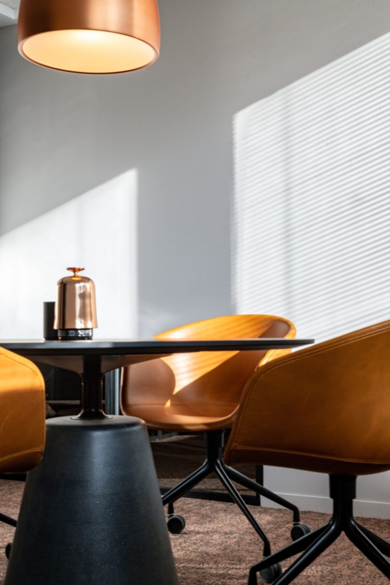 Chaises en cuir marron et suspension en cuivre dans une salle de réunion chic, conçue par JoyDesign Intérieur pour un cabinet d'avocat.