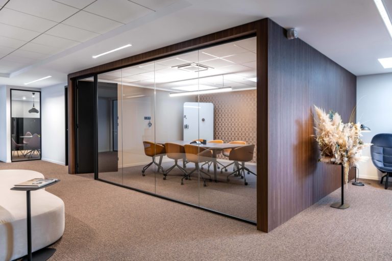 Salle de réunion vitrée avec des chaises en cuir marron et des accents de cuivre, conçue par JoyDesign Intérieur pour un cabinet d'avocat