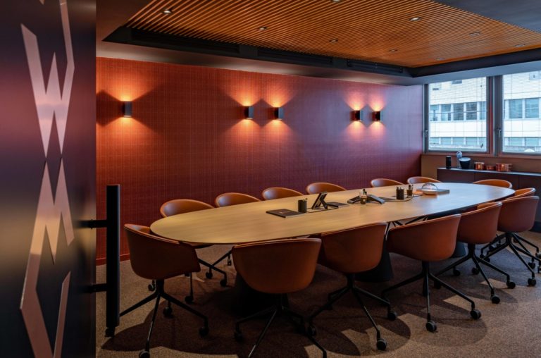 Salle de réunion élégante avec des murs rouge foncé, des chaises en cuir marron et une grande table en bois, conçue par JoyDesign Intérieur pour un cabinet d'avocat.