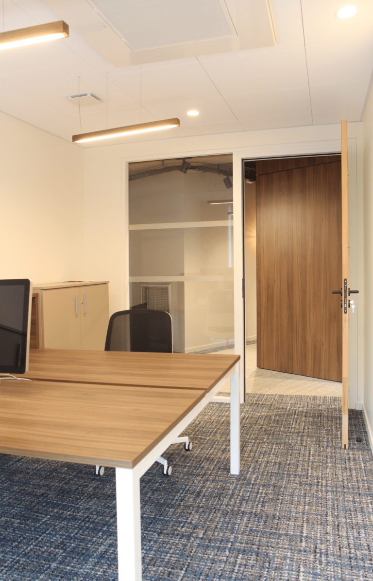 Bureau fermé moderne et lumineux dans des bureaux de 700m², équipé de mobilier en bois et de luminaires suspendus, conçu par JoyDesign Intérieur.