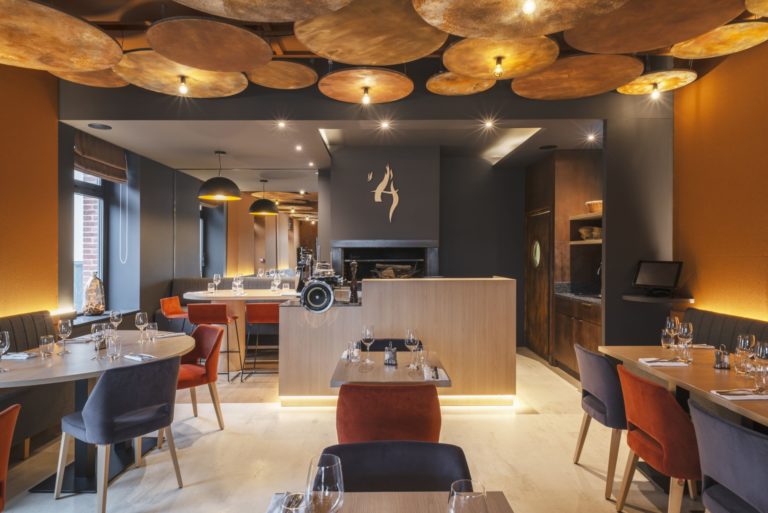 Intérieur du restaurant L'Âtre à Rennes avec des tons chauds et un plafond en acier corten, conçu par JoyDesign Intérieur pour évoquer la chaleur des flammes.