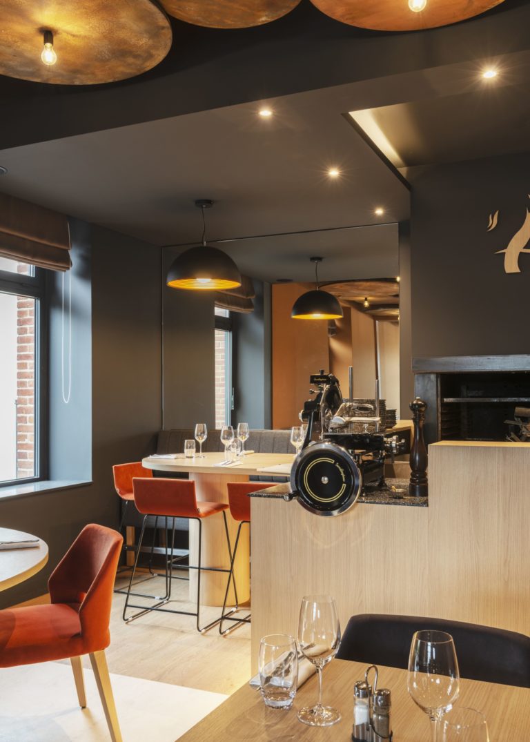 Intérieur du restaurant L'Âtre à Rennes avec des tons chauds et des éléments en acier corten, conçu par JoyDesign Intérieur pour évoquer la chaleur des flammes.