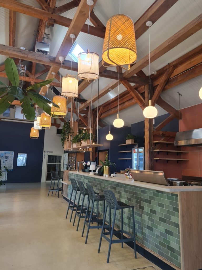 Salle de réception avec un bar en carreaux verts et des luminaires en osier au Domaine de la Ville Huchet à Saint-Malo.