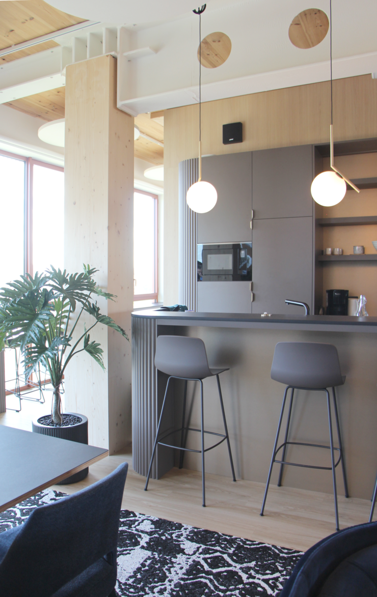 Photo d'un coin bar moderne et élégant avec des tabourets hauts, des luminaires suspendus et des éléments en bois clair.