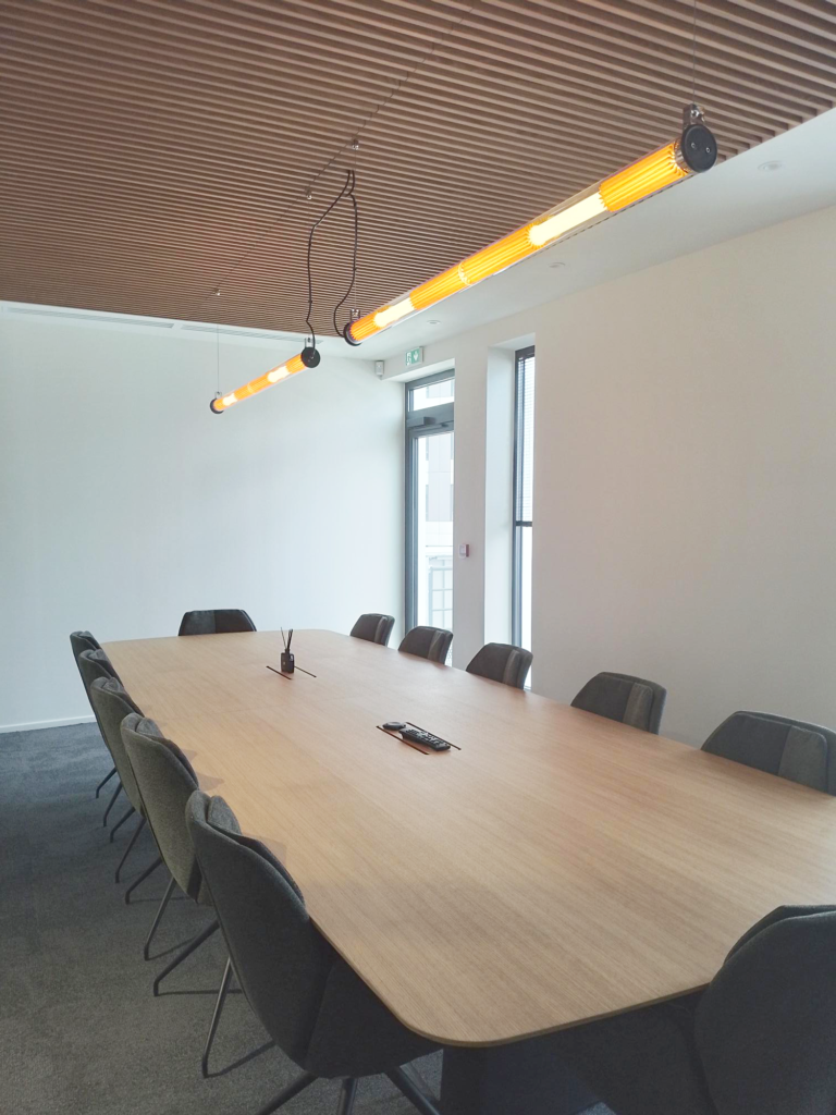 Grande salle de réunion avec table en bois et plafond lamellé.